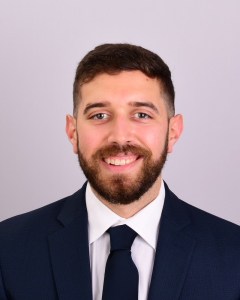 Headshot of Dr. Alexander Faigen smiling wearing a suit and tie